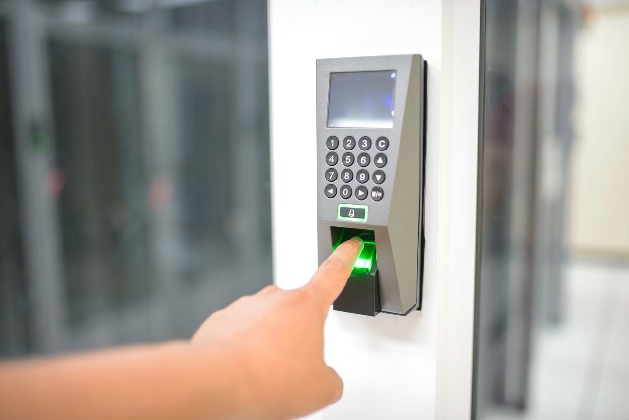 Home A person uses a fingerprint scanner for secure entry in a business setting.
