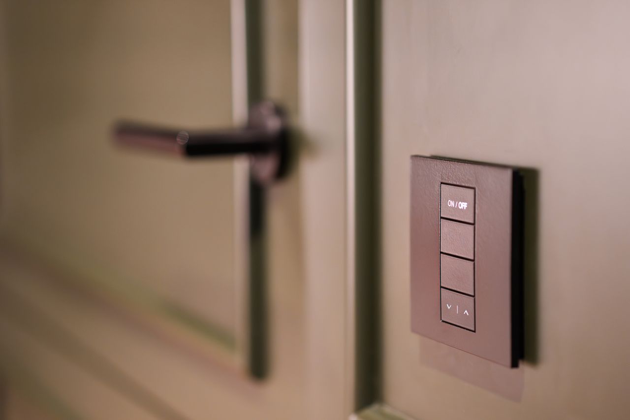 Home A smart light switch on a wall next to a modern door handle, emphasizing home automation.